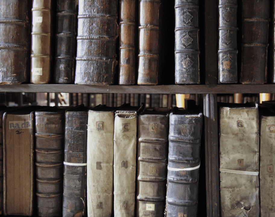 Close up of the spines of old books on a shelf
